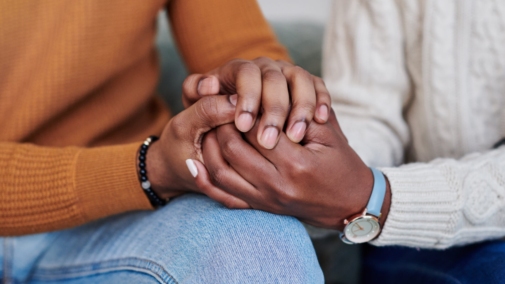 Closeup shot of an unrecognisable couple holding hands while relaxing together at home